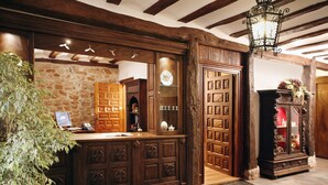A reception area with a wooden desk, stone wall, and a large wooden door.
