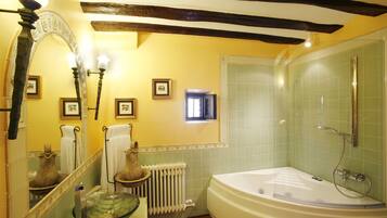Une salle de bain avec une grande baignoire, un miroir orné d’un arc décoratif et une fenêtre.