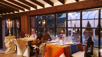 A dining area with tables set for a meal, large windows, and a view of the outdoors.