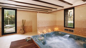 A spa area with a hot tub, wooden flooring, tiled walls, and a window with a view of greenery.