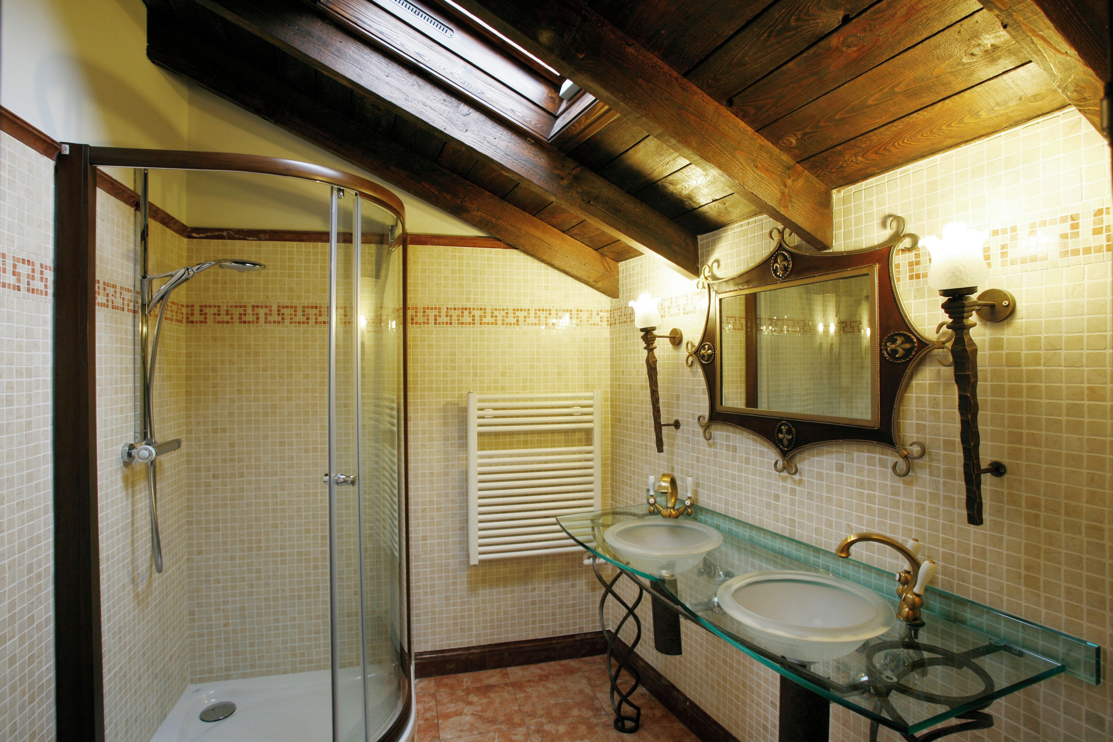 Un baño con cabina de ducha de vidrio, dos lavamanos con encimeras de vidrio y un espejo grande sobre los lavamanos.