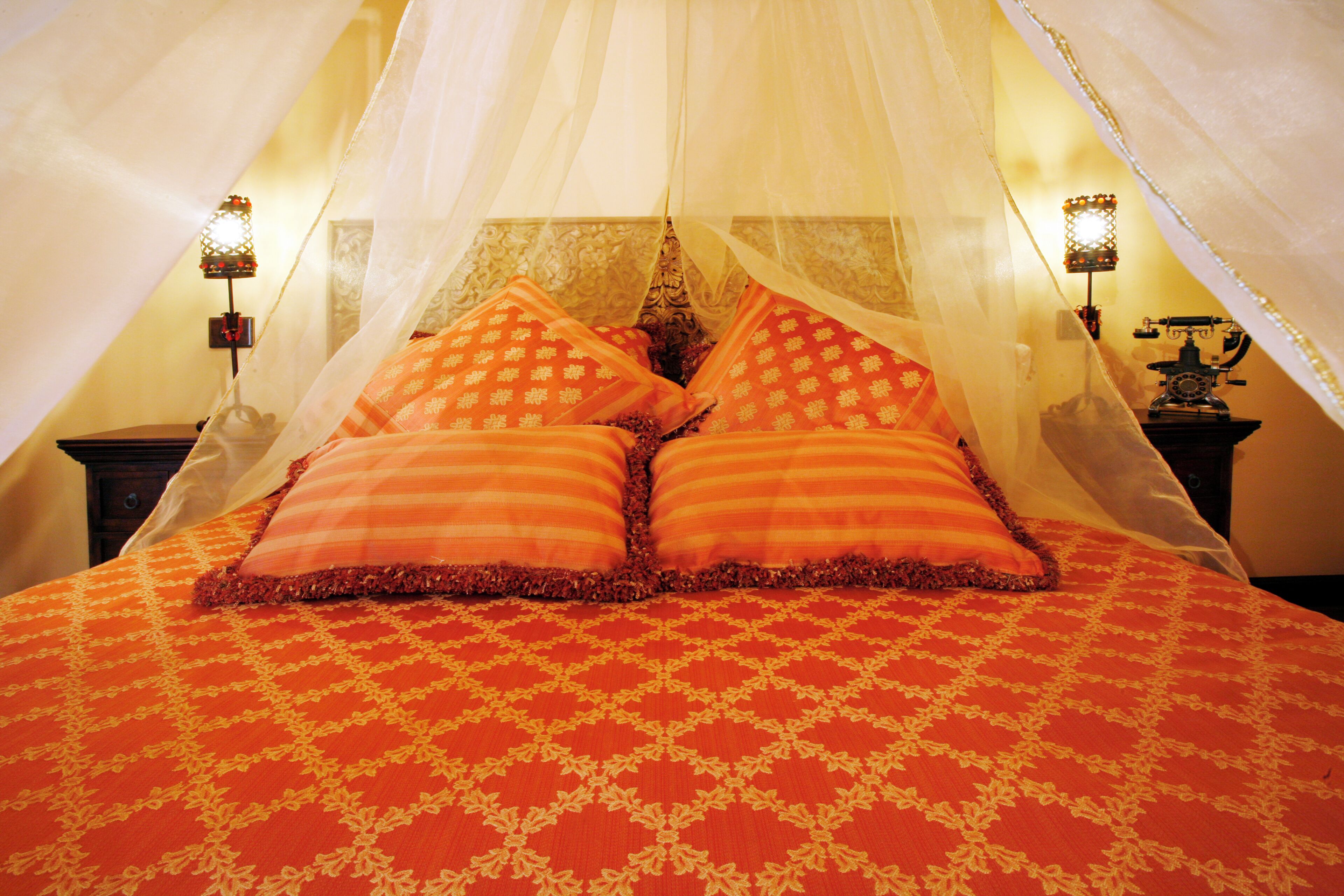 Ein Bett mit Baldachin, zwei Kissen und einer gemusterten Tagesdecke.