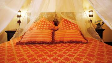 Ein Bett mit Baldachin, zwei Kissen und einer gemusterten Tagesdecke.
