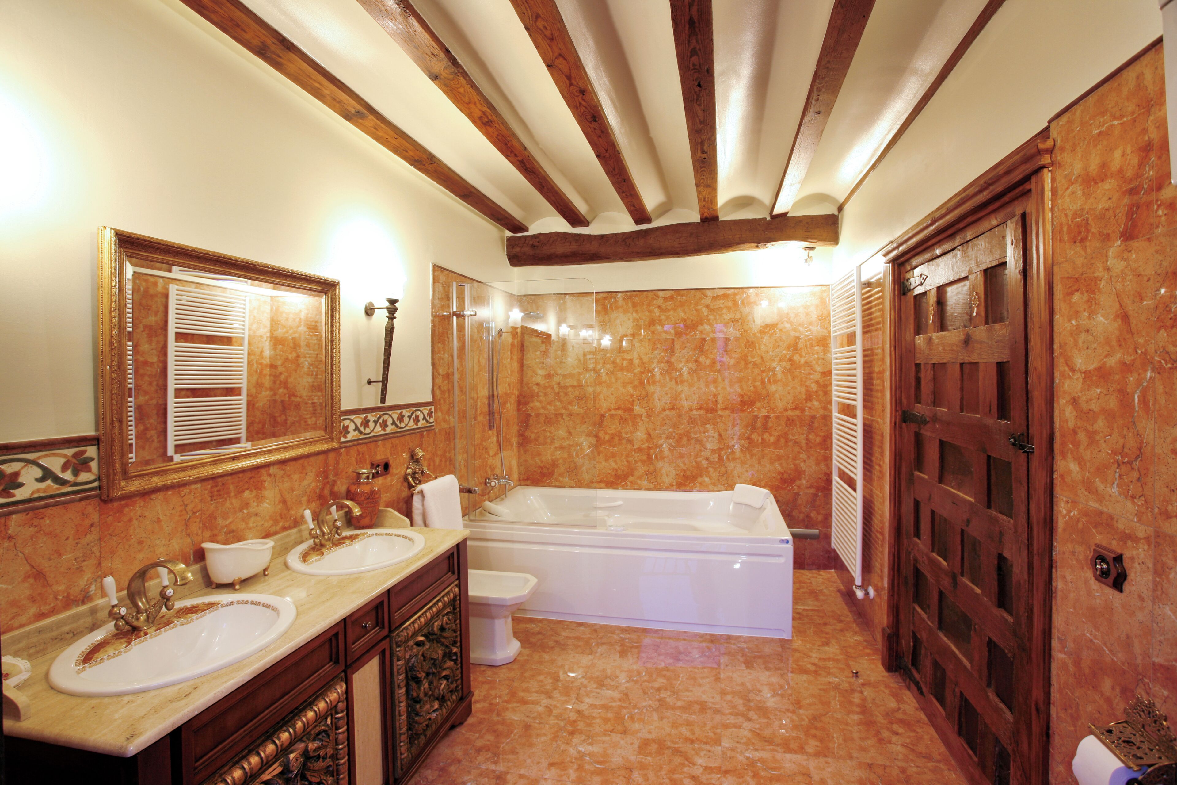 A bathroom with a double sink, a bathtub, and a large mirror.