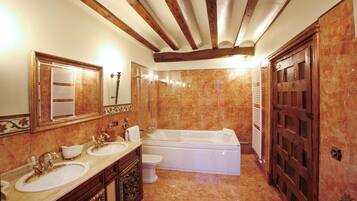 A bathroom with a double sink, a bathtub, and a large mirror.