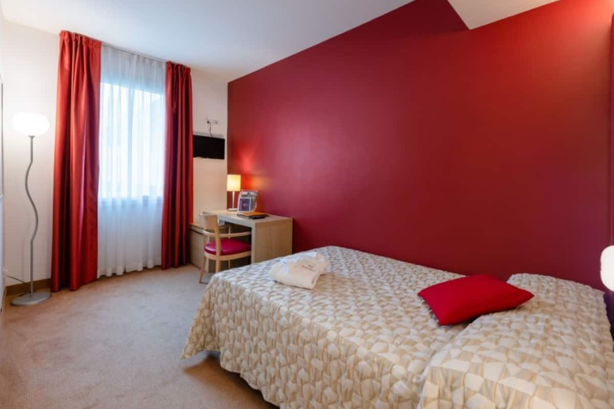 Une chambre d’hôtel avec un lit, un bureau et une chaise.