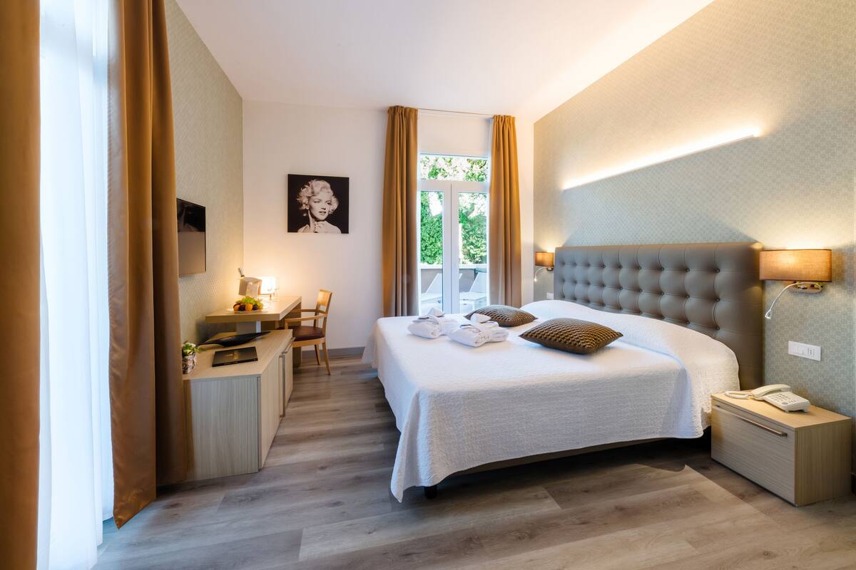 Une chambre d’hôtel comprenant un lit, une table de chevet, une lampe et un bureau avec une chaise.