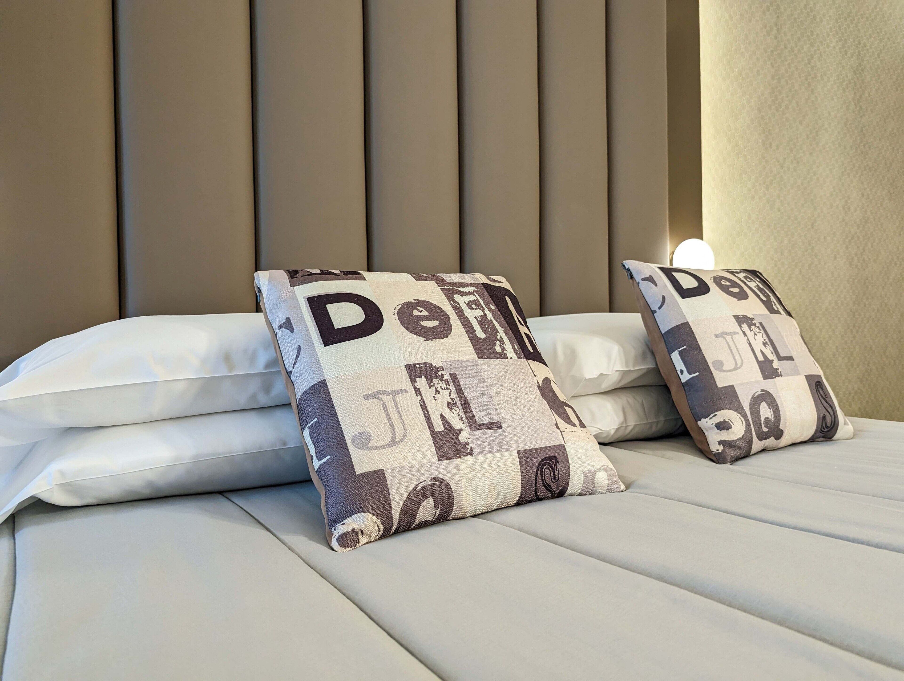 A bed with two decorative pillows featuring a pattern of letters and numbers.