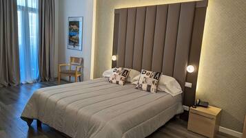 Un cuarto de hotel ordenado con una cama grande, una mesita de noche con un teléfono y una silla.