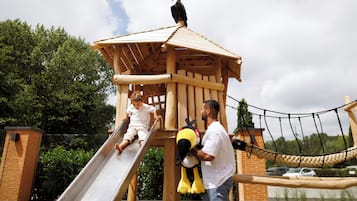Een houten speelconstructie met een glijbaan, een klimgedeelte en een touwbrug.