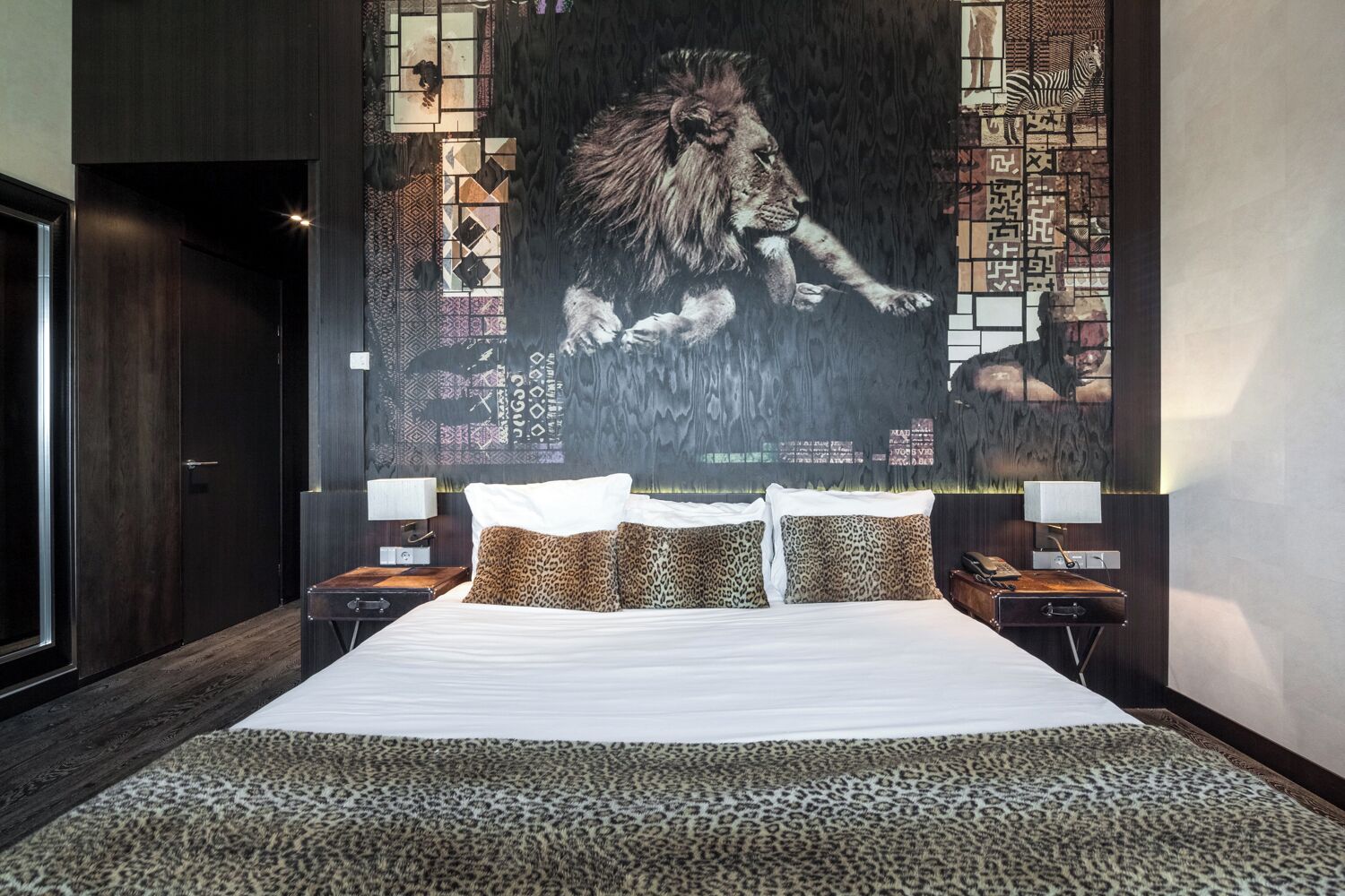 A bedroom with a large bed, a leopard print rug, and a wall with a lion mural.