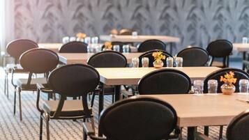 A conference room with multiple tables and chairs, arranged in rows.