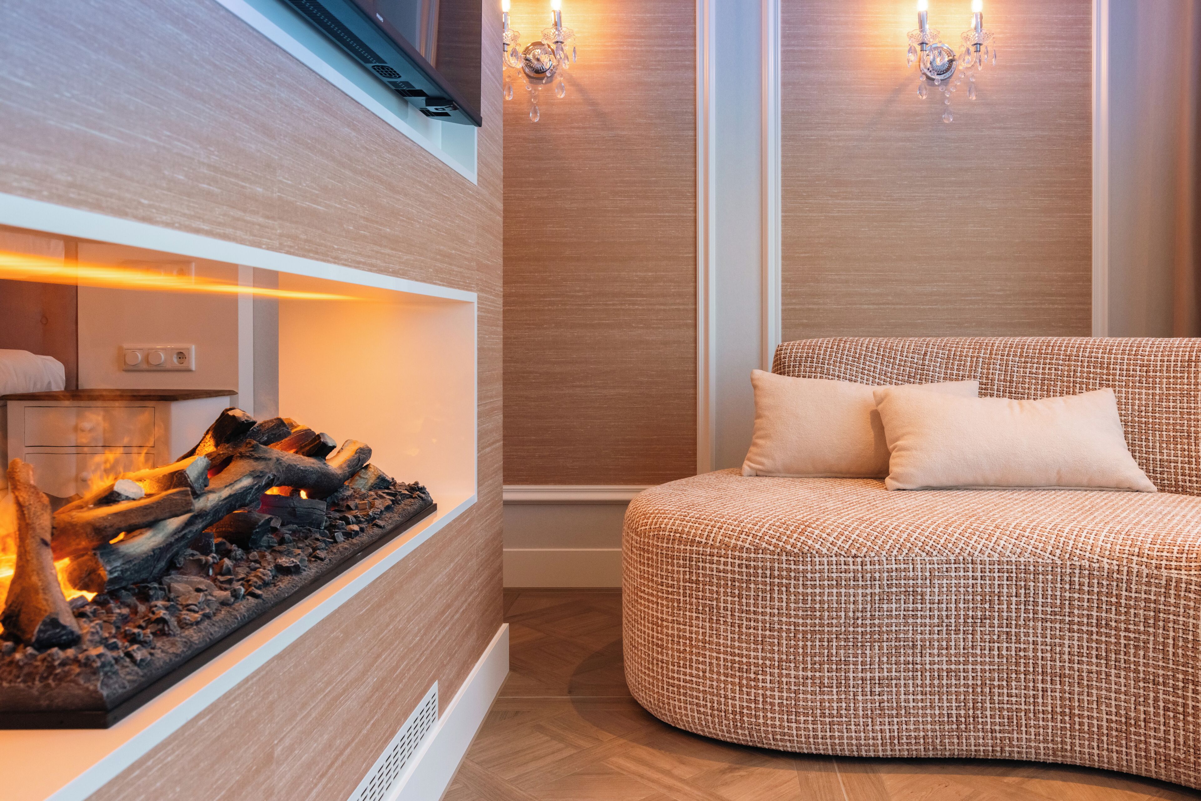 A modern interior with a built-in fireplace, a cozy seating area with a patterned sofa, and wall-mounted lighting fixtures.