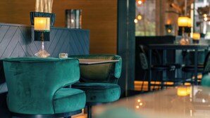 Een modern interieur met een smaragdgroene gestoffeerde bank, een glazen salontafel en een decoratieve lamp.