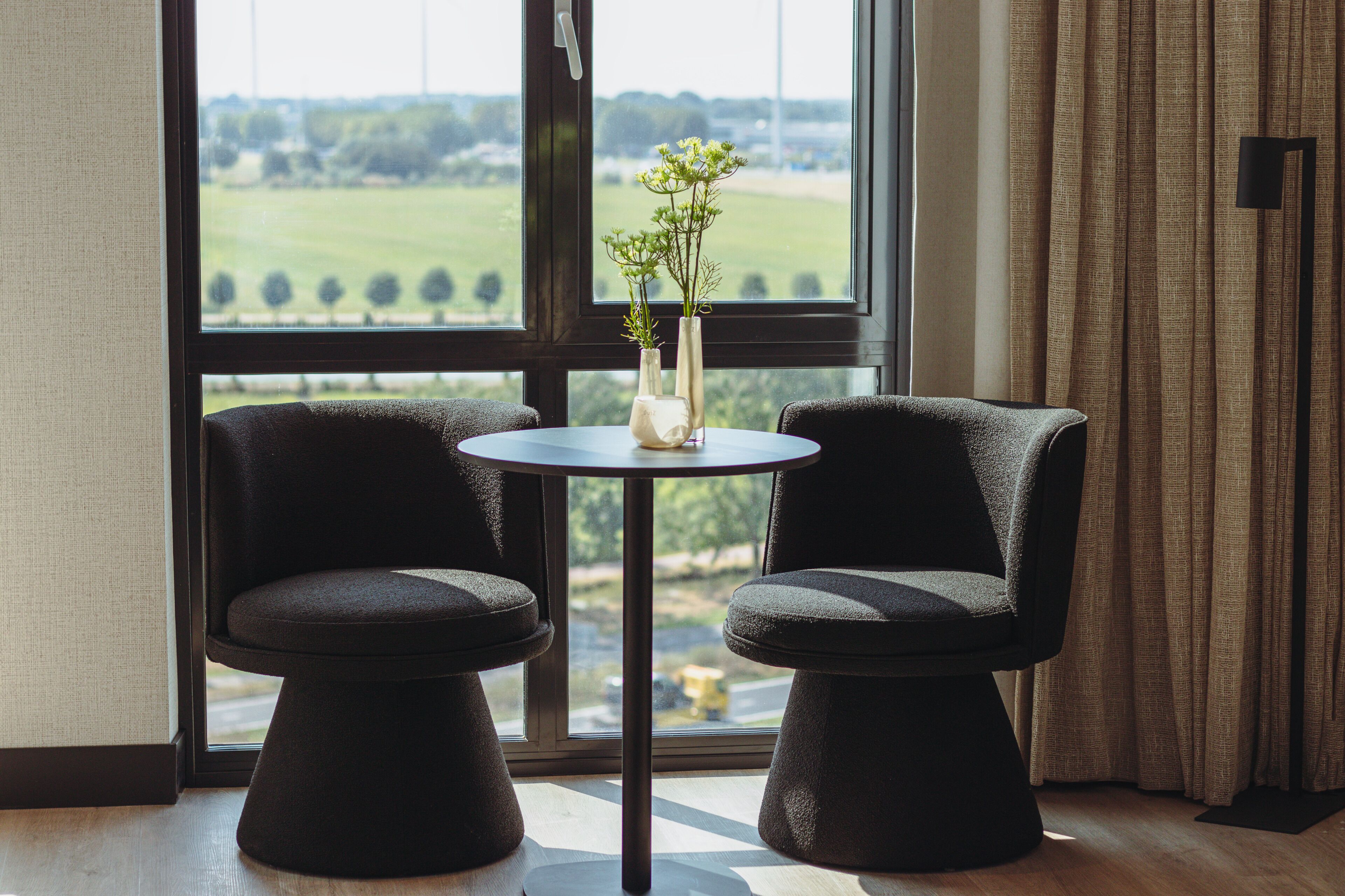 Une pièce comprenant deux fauteuils rembourrés, une petite table ronde et un vase avec des fleurs.