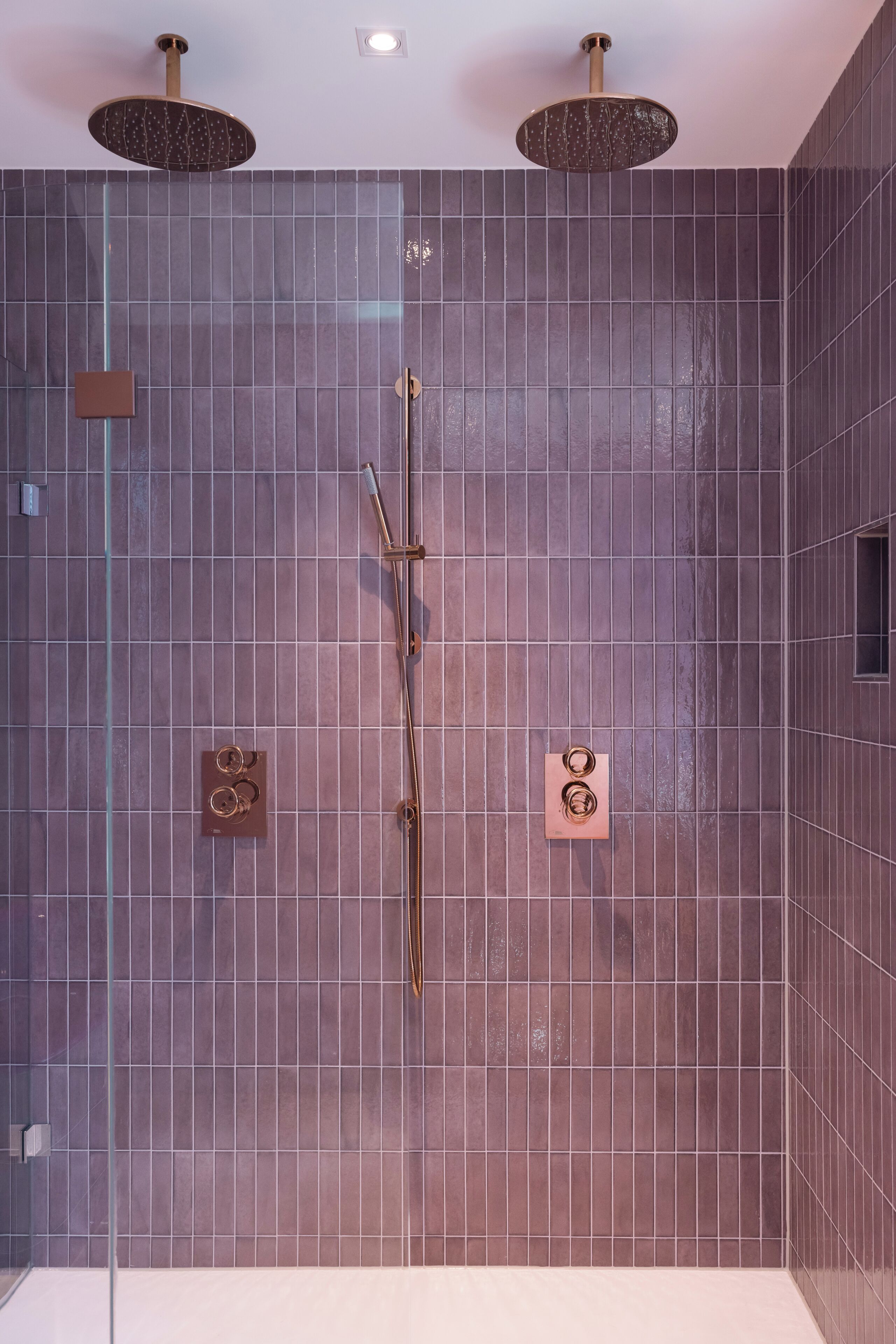 A modern bathroom with a large shower area, a glass enclosure, and a wall-mounted control panel.