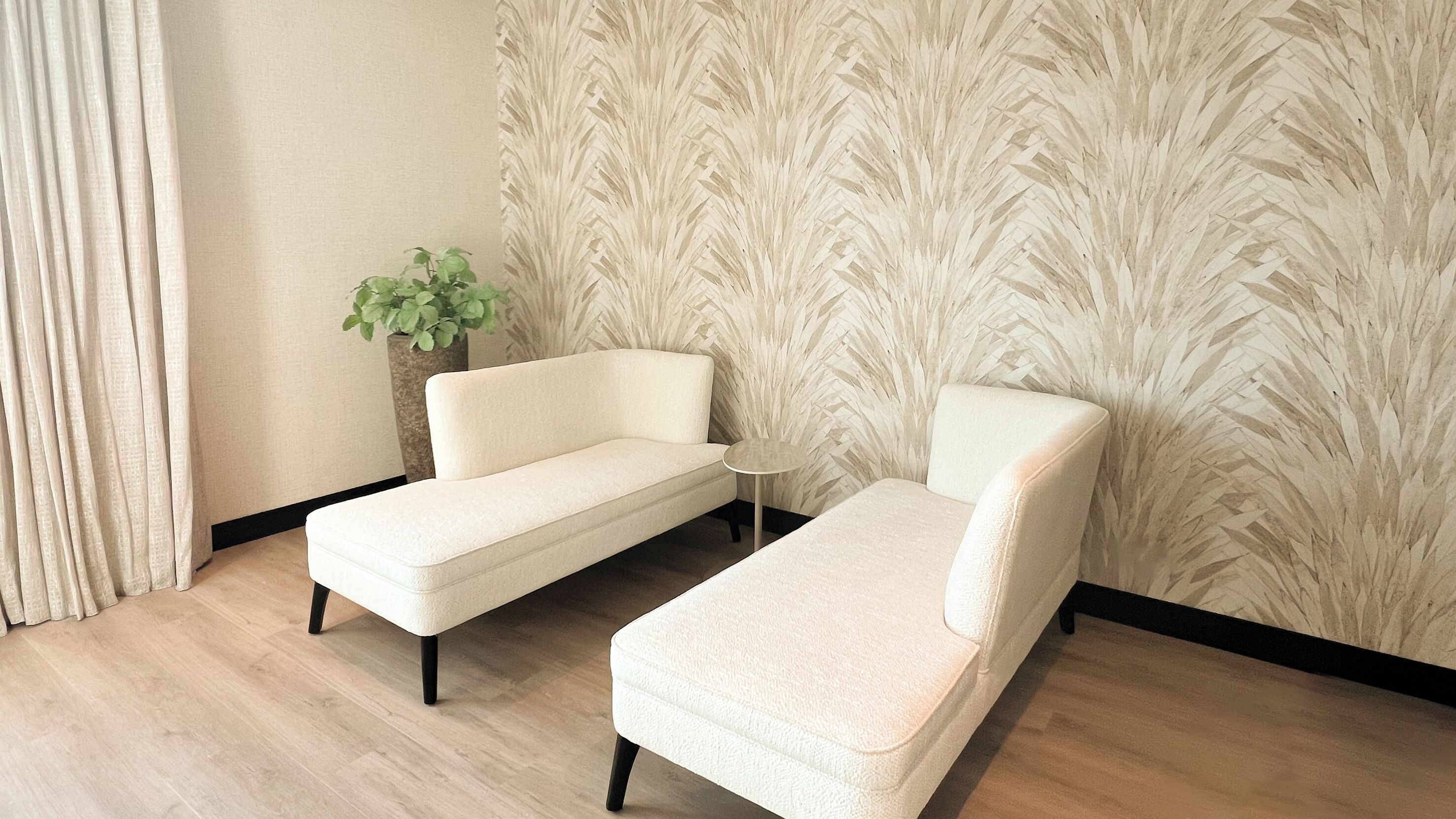 A room with two white sofas, a small round table, and a potted plant.