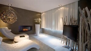 Een moderne woonkamer met een open haard, een televisie en een zithoek.