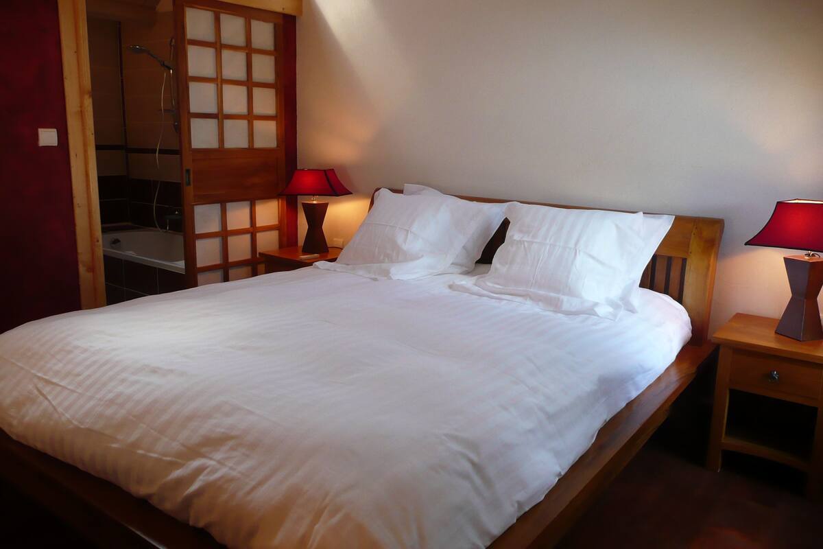A neatly made bed with white linens, two bedside tables with lamps, and a wooden headboard.