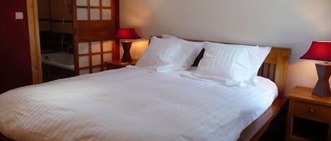 A neatly made bed with white linens, two bedside tables with lamps, and a wooden headboard.