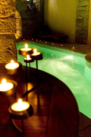 A stone wall, a pool with candles, and a wooden bench. - Manoir des Indes, The Originals Relais (Quimper)