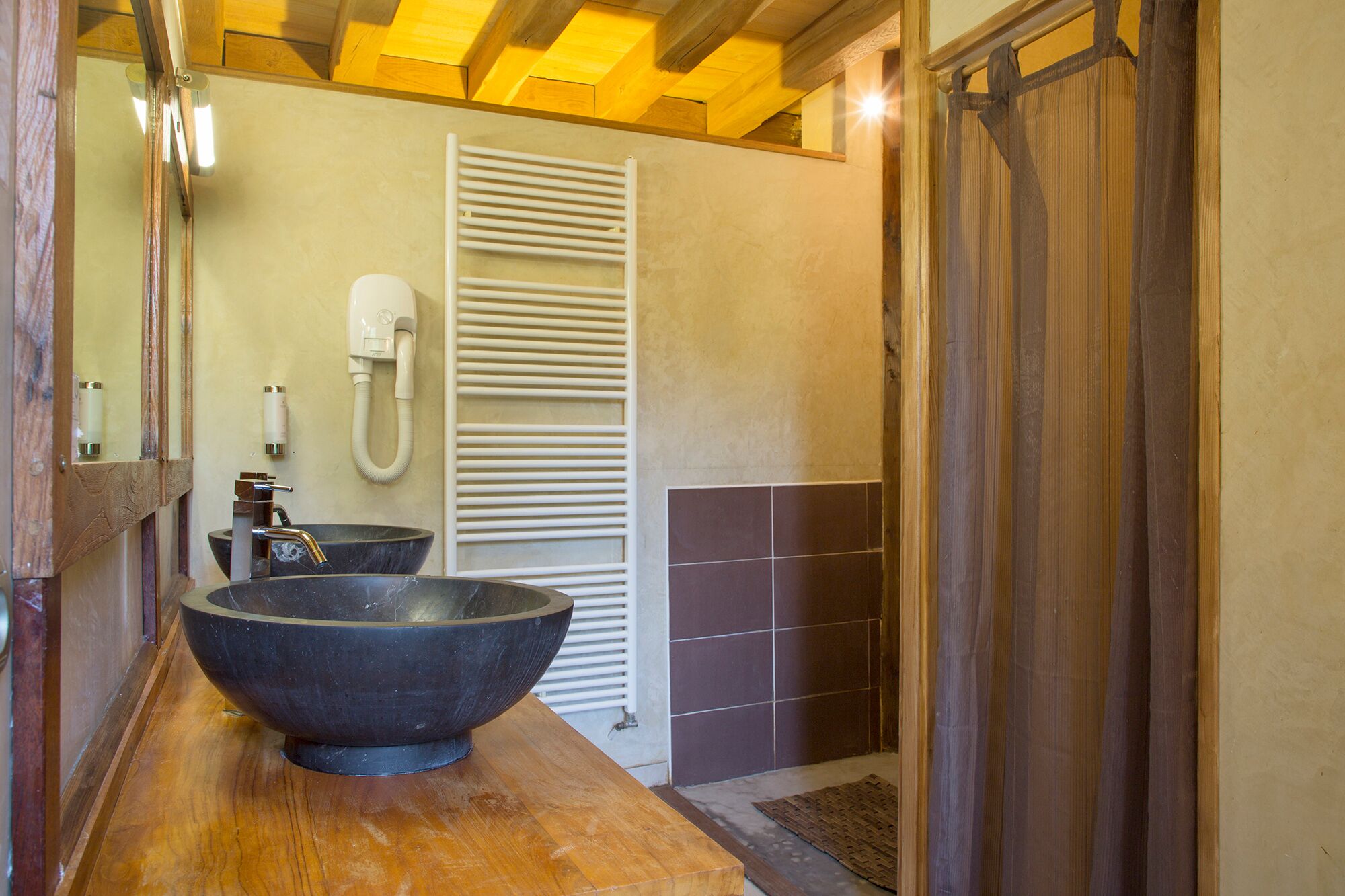A bathroom with a large bowl sink, a towel rack, and a shower area.