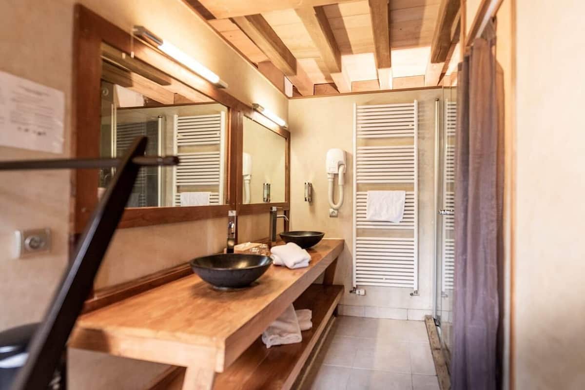A bathroom with a wooden vanity, a large mirror, a towel rack, and a towel hanging on it.