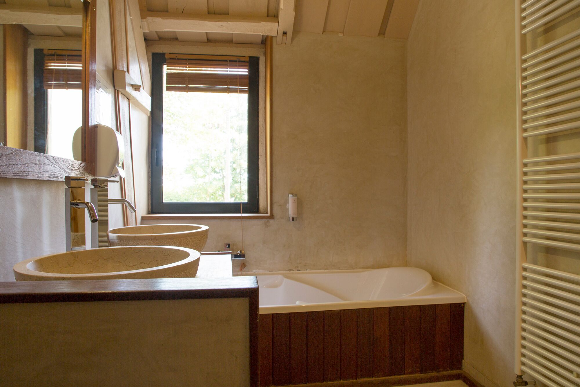 A bathroom with a bathtub, two sinks, a window, and a radiator.