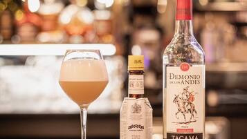 Un bar avec une bouteille de pisco Demonio de los Andes Tacaima, une bouteille d’amer Angostura et un verre de cocktail.