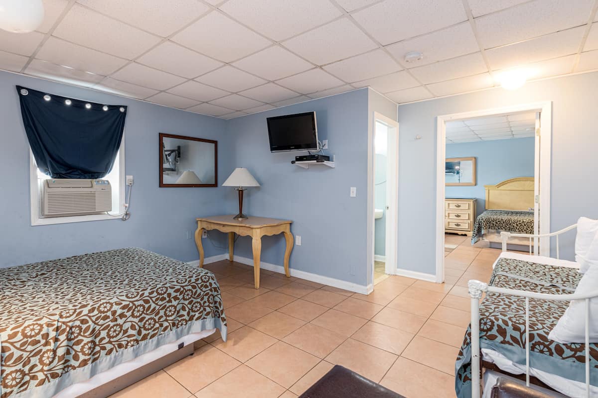 Un dormitorio con dos camas, televisión, escritorio y ventana con cortinas.
