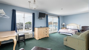 Habitación de hotel con cama, escritorio, cómoda y una silla. Cuenta con ventana con cortinas, un televisor montado en la pared y una lámpara en la mesita de noche.