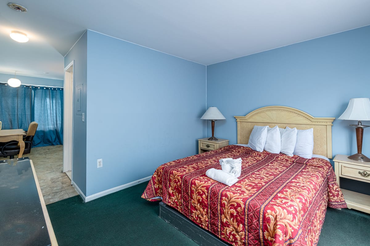 Una habitación de hotel con una cama grande, dos mesitas de noche con lámparas, un escritorio y una silla.