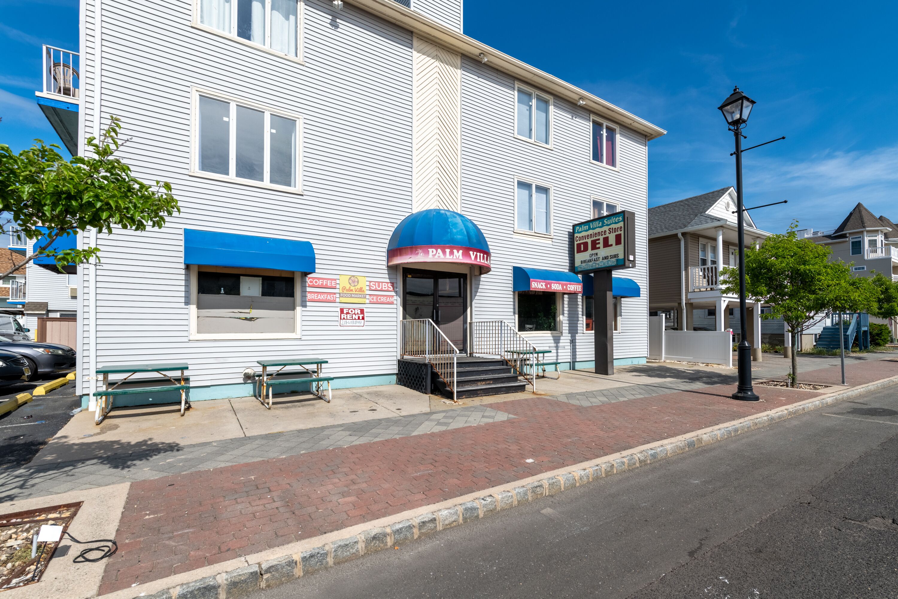 A two-story building with a blue awning and a sign for 'Palm Villa'.