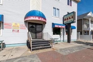 A building with a sign reading "Palm Villa" and "Convenience Store Deli" with a blue awning.