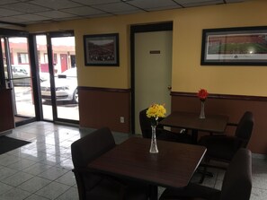 L’intérieur d’un restaurant, avec des tables, des chaises, une porte portant l’inscription « PRIVÉ » et un tableau encadré accroché au mur.