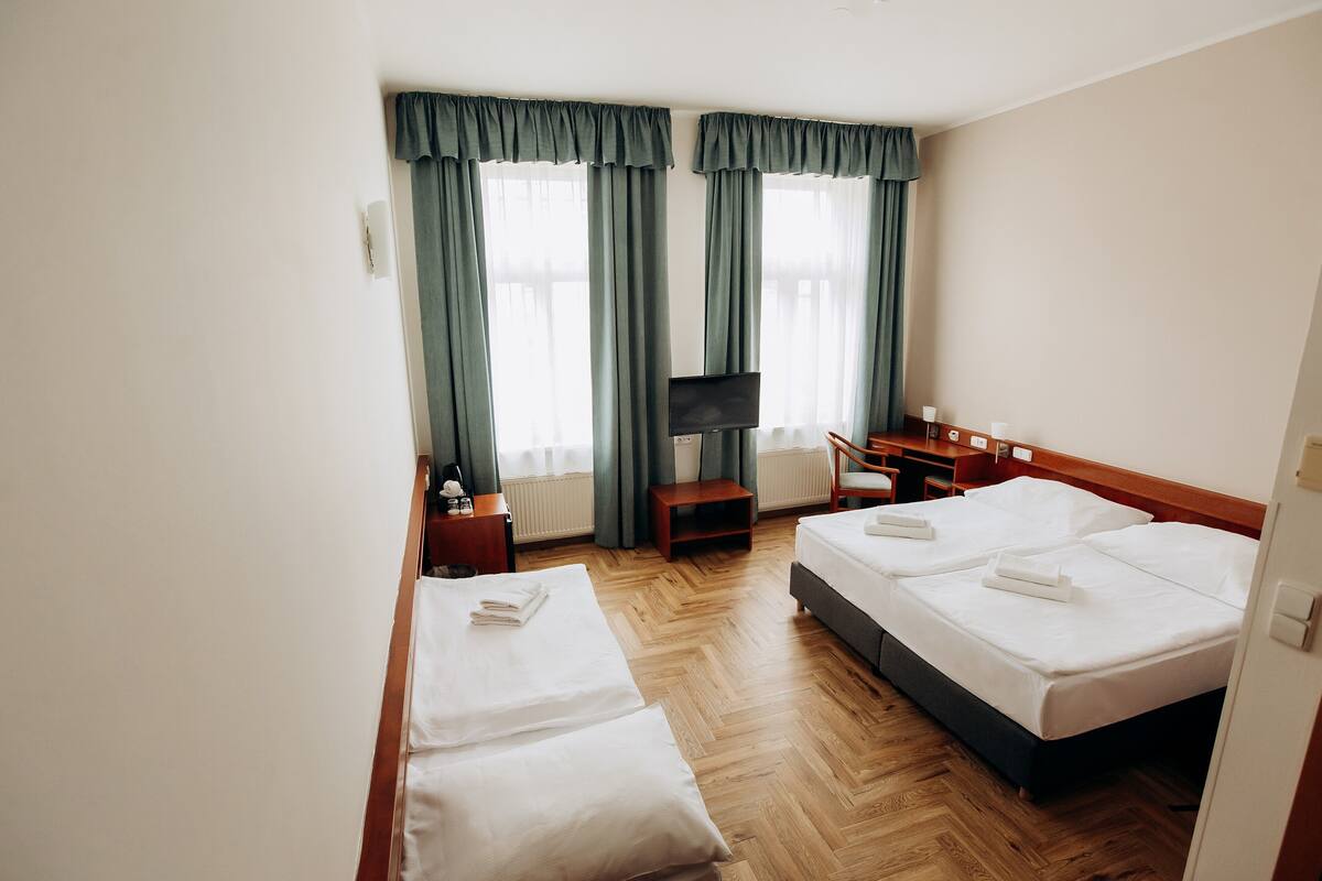 Quarto de hotel com duas camas, televisão, escrivaninha e uma cadeira.