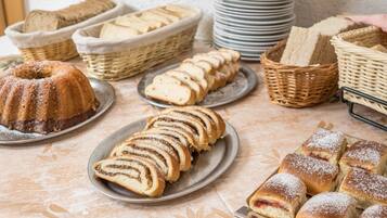Uma mesa com diversos produtos de panificação, incluindo um bolo bundt, pão fatiado e doces.