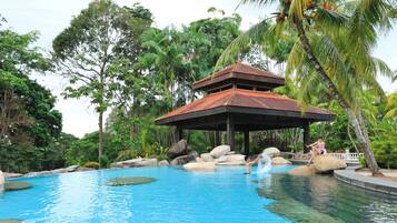 A pool with a gazebo, surrounded by palm trees and rocks.