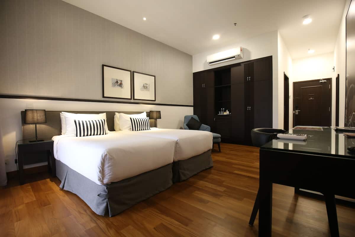A hotel room with a large bed, a desk, and a wardrobe.
