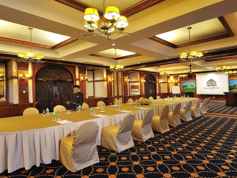 A conference room with a long table, chairs, and a projector screen displaying a presentation.