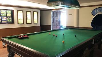 A pool table with balls, a notice sign, framed pictures, and a door with a sign.