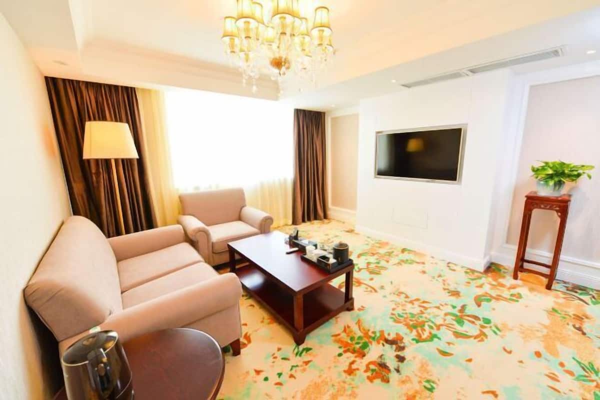 A hotel room with a sofa set, a coffee table, a TV, and a patterned carpet.