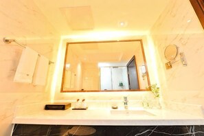 A bathroom with a large mirror, a sink, a towel rack, and a toilet visible in the reflection.