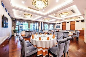 A conference room with round tables, chairs, and a television screen.