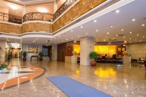 A hotel lobby with a reception desk, seating area, and a curved floor design.