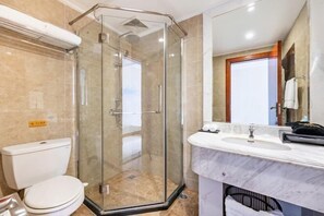 A modern bathroom with a glass-enclosed shower, a white toilet, and a marble sink.