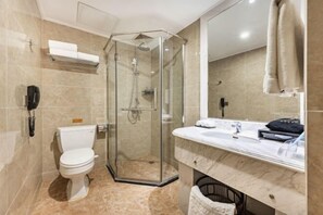 A modern bathroom with a glass-enclosed shower, a toilet, and a vanity with a mirror.