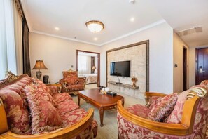 A living room with a sofa set, a television mounted on a stone wall, and a fireplace.