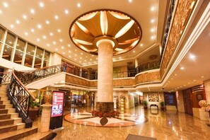 A multi-level hotel lobby with a central column, a staircase, and a circular decorative feature. - River Romance Hotel (Chongqing Jiefangbei) (Chongqing)