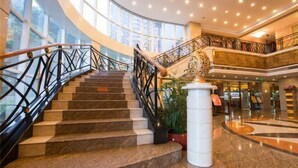 Una imponente escalera con barandilla de metal negro que conduce a un balcón en el segundo piso con vistas a la ciudad.